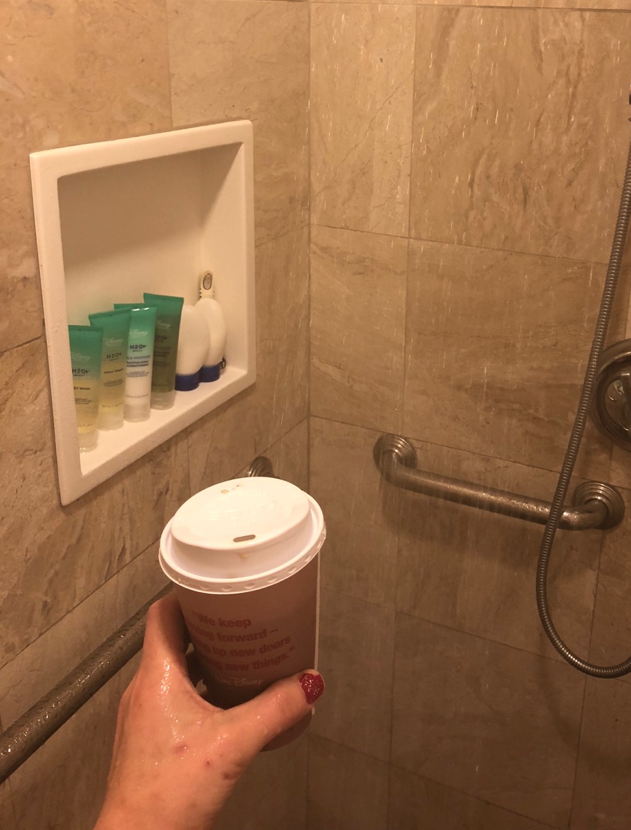 Amelia holding a coffee in the shower